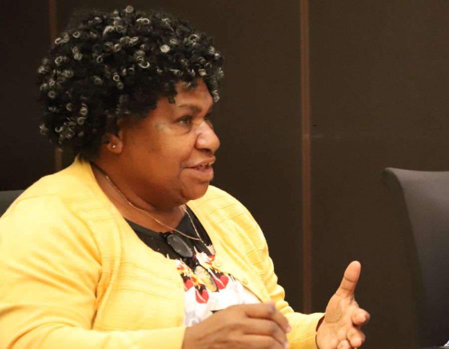 Woman in yellow cardigan sitting and speaking