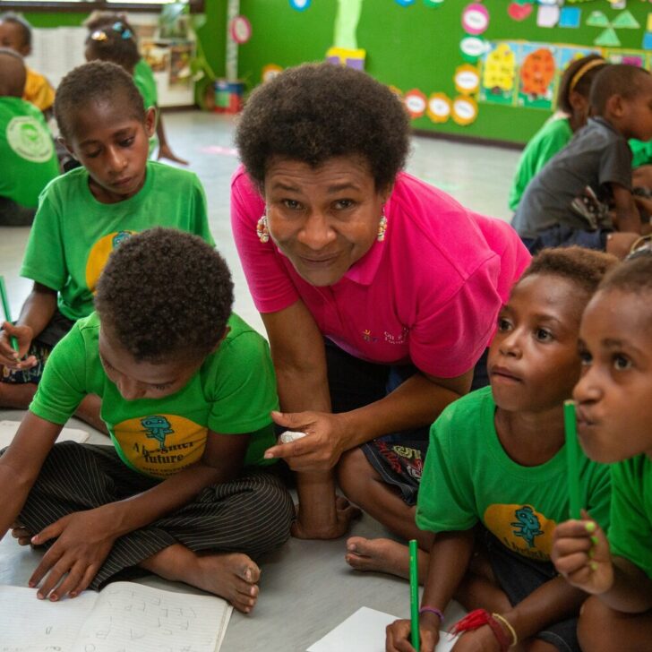 Kikori community member teaching children writing skills